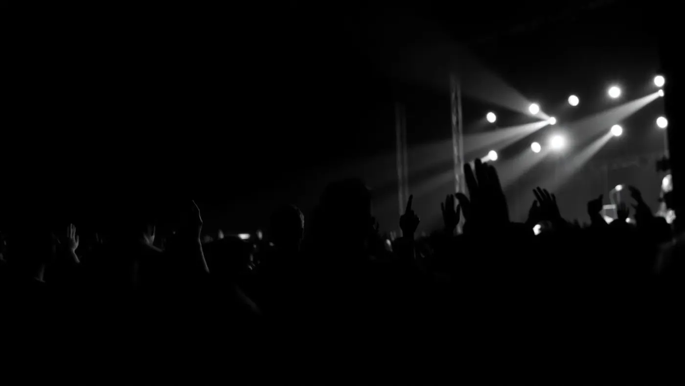 Plateia de festival de música com luzes de palco ao fundo